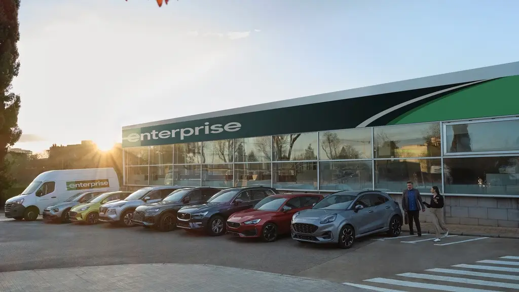 An Enterprise branch with its green canopy and a lineup of rental vehicles at golden hour