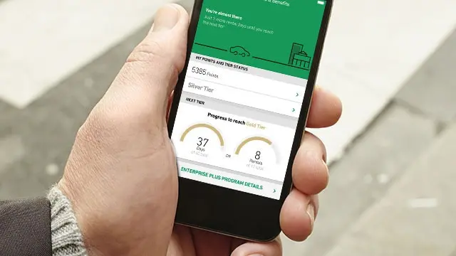 A hand holds a phone showing the Enterprise app