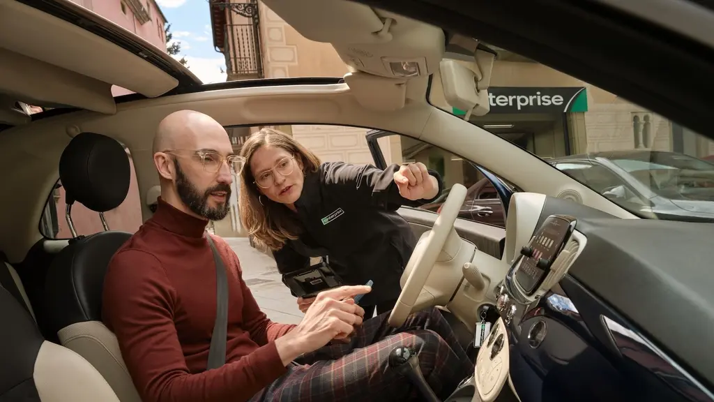An Enterprise employee walks a customer through the features of a rental car
