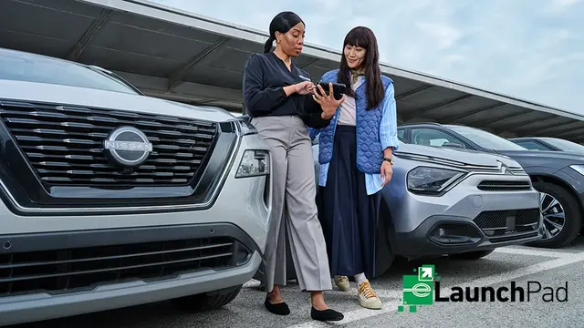 An Enterprise employee reviews a tablet with a customer beside a vehicle, with LaunchPad branding